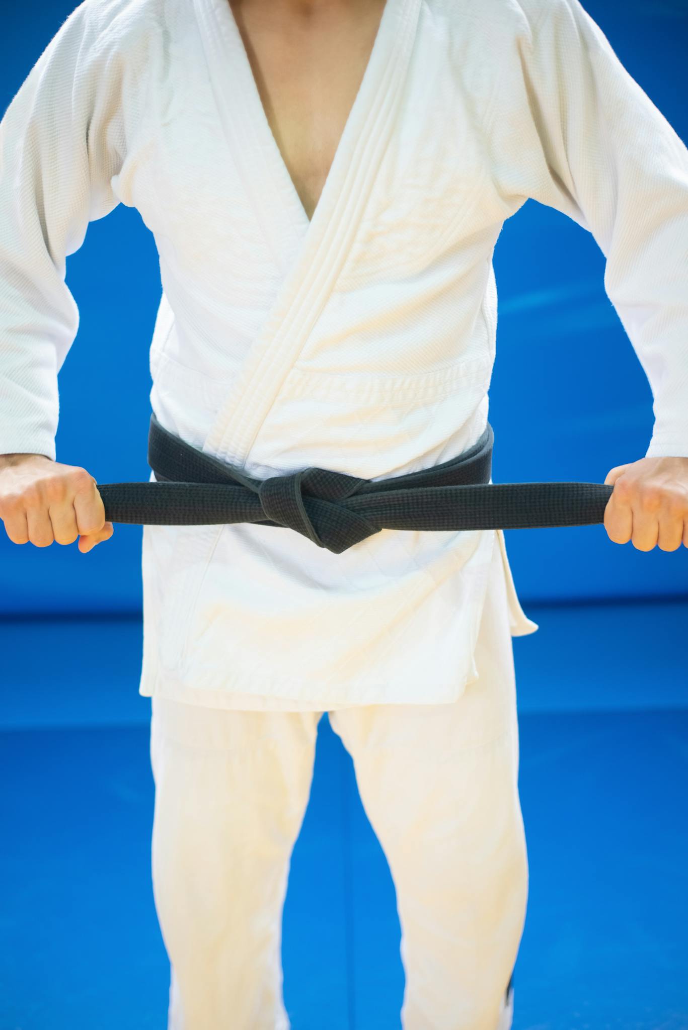 A Person wearing Judo Uniform holding his Black Belt