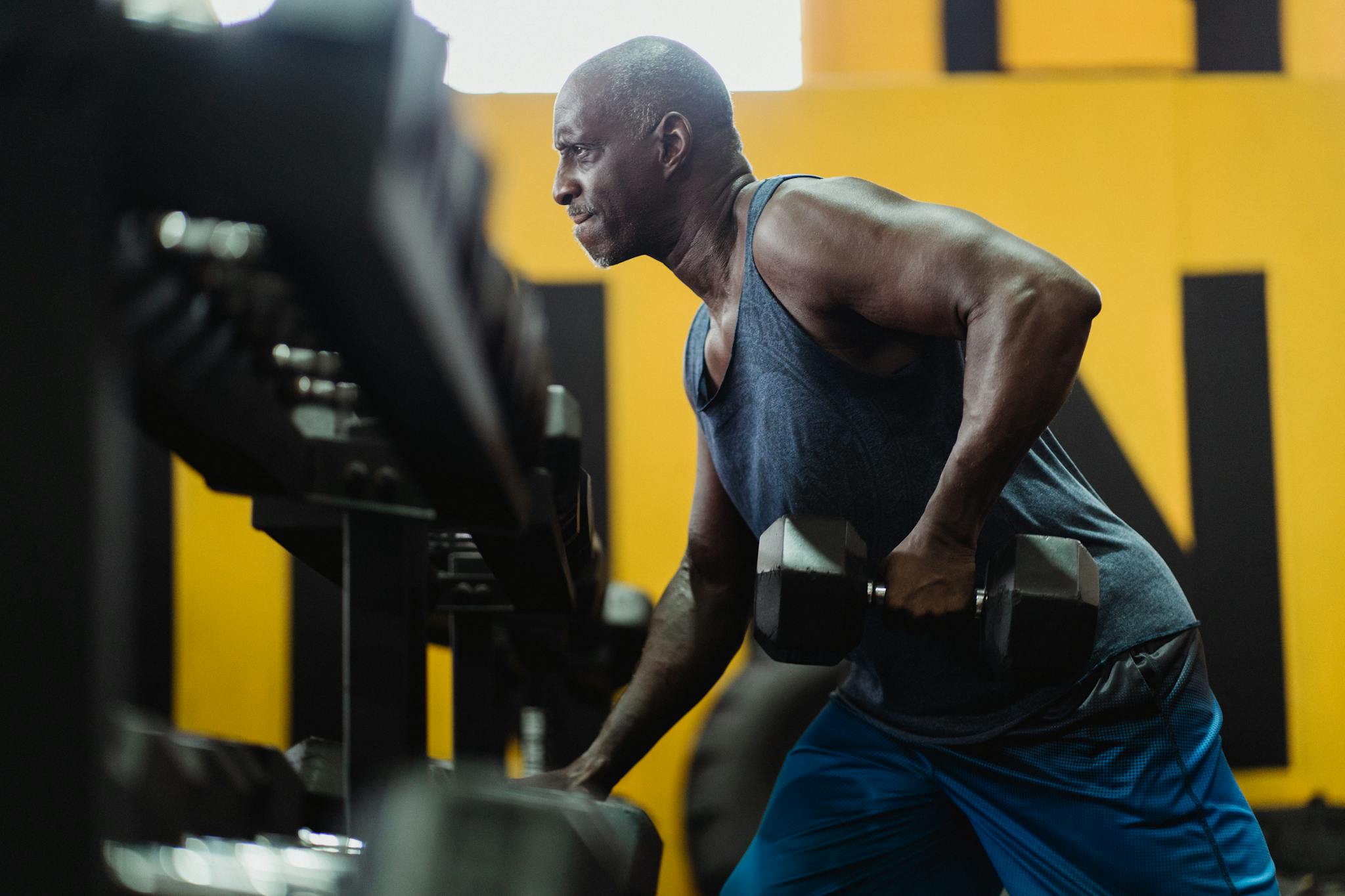 Man in Blue Tank Top Lifting a Heavy Dumbbell